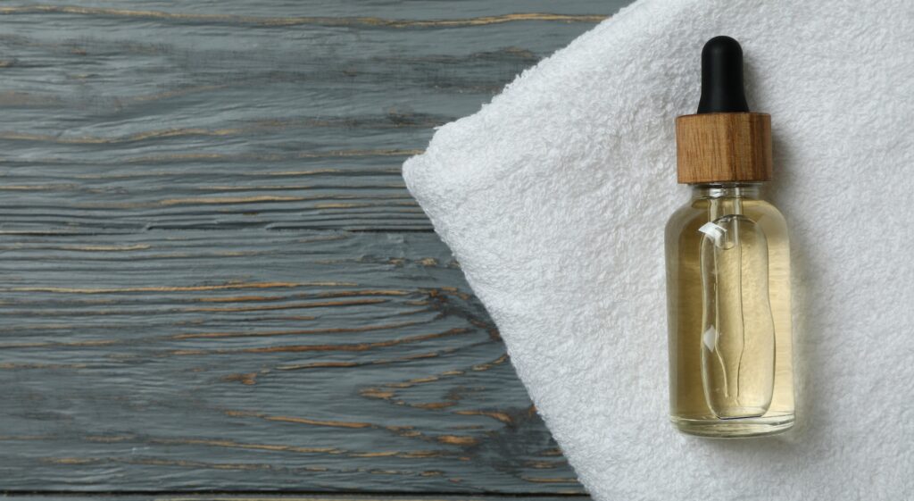 Dropper bottle with oil on towel on wooden background